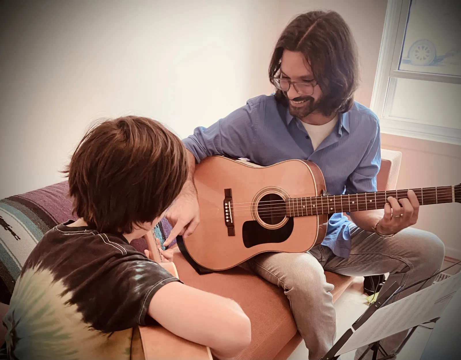 Keith McCuaig teaching a young student to play acoustic guitar